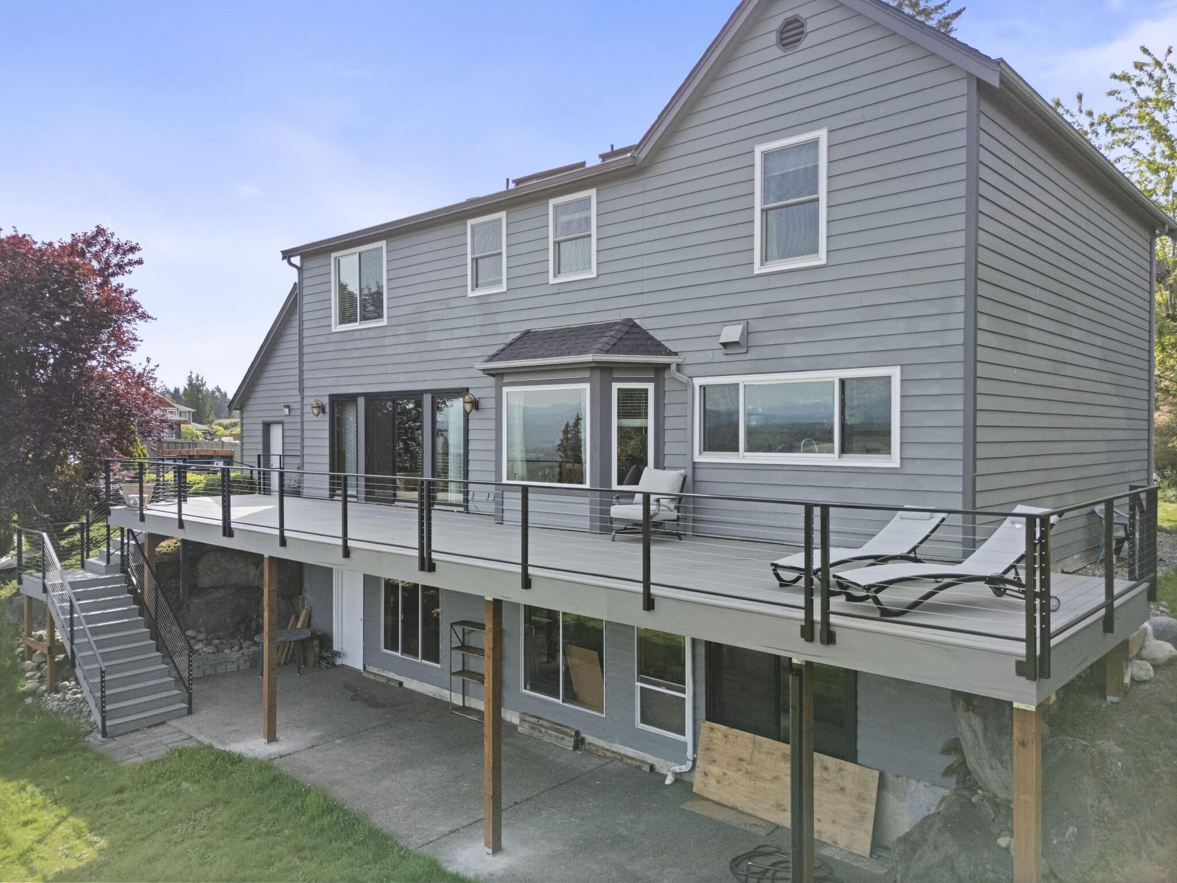 A completed two-story deck remodel by BB-Builders Pro — gray home, cable railings, mountain view